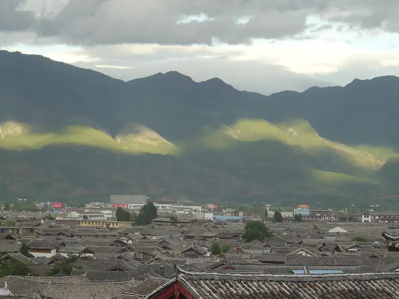 Tiled rooftops of Lijiang Old Town with mountains behind